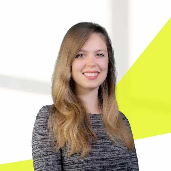 Saskia Wagner, meliertes schwarzes langärmeliges Oberteil, mit offenem braunen langem Haar, direkter Blick in die Kamera, lächend