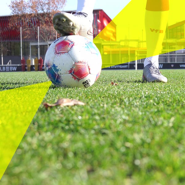 Der Fußball 2026 wird stabil gehalten von einem Fuß in Fußballschuhen und VfB Stuttgart Socken. Das andere Bein steht fest daneben.